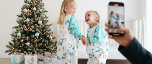 two girls dancing in front of a christmas tree