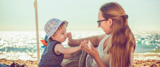 mum putting sun cream on a baby on the beach