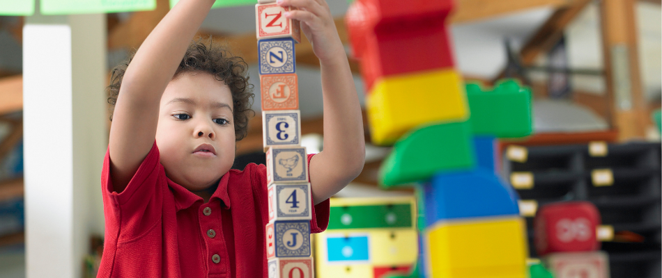 boy in red top building blocks at school