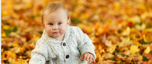 baby sitting in autumn leaves