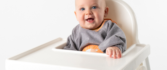 baby in high chair in grey baby bib