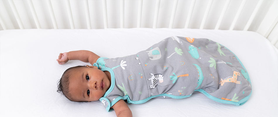 baby in baby sleeping bag in cot