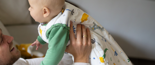 dad holding baby up in jungle white and green baby sleeping bag