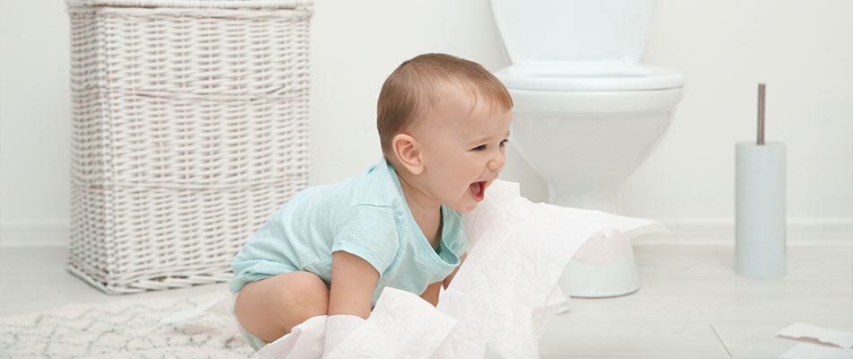 baby sitting in the bathroom in front of a toilet