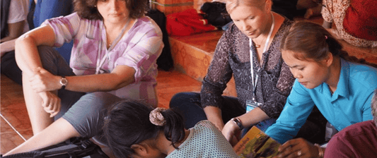 women watching a cambodian lady work 