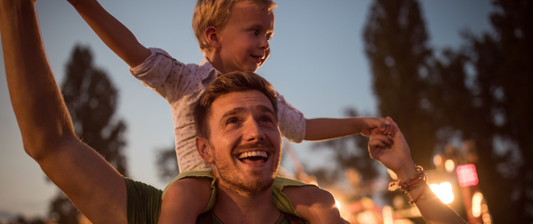 man with toddler on shoulders at a festival