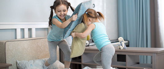 two girls pillow fighting on a sleepover